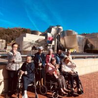 Un grupo de personas mayores, posando delante del Museo Guggenheim de Bilbao